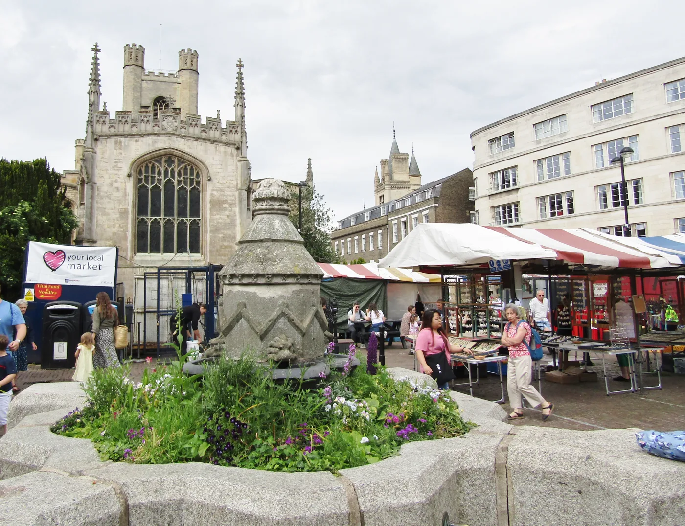 The listed fountain and market stalls on Cambridge Market Square. The scheme relays the listed setts but does not bring the fountain back into use