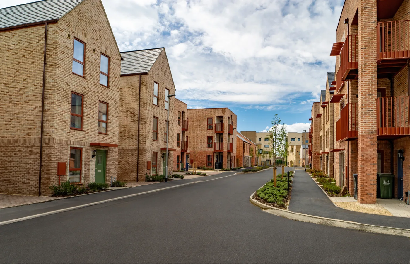 A street of brick houses and apartment blocks with balconies at Darwin Green, Cambridge